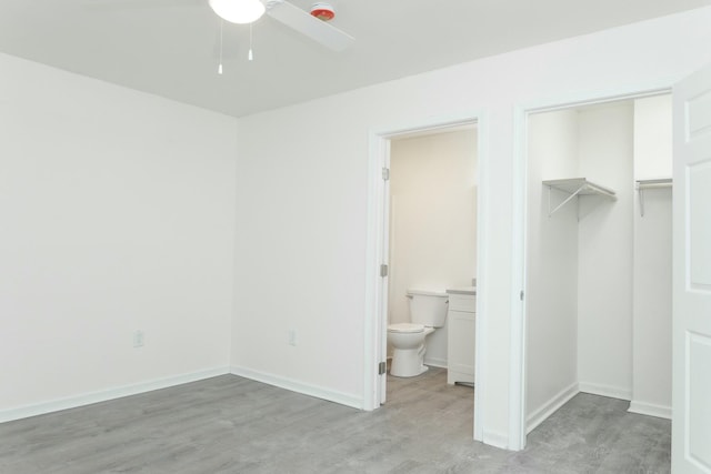 unfurnished bedroom with ensuite bathroom, ceiling fan, a spacious closet, light hardwood / wood-style floors, and a closet