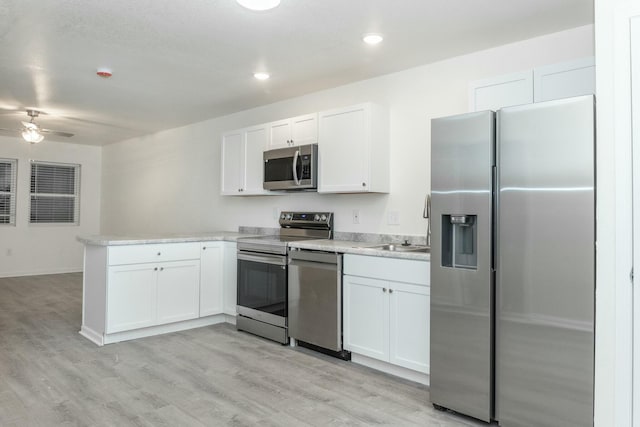 kitchen with white cabinetry, ceiling fan, stainless steel appliances, kitchen peninsula, and light wood-type flooring