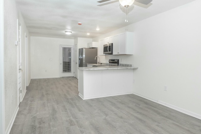 kitchen featuring kitchen peninsula, appliances with stainless steel finishes, sink, white cabinets, and light hardwood / wood-style floors