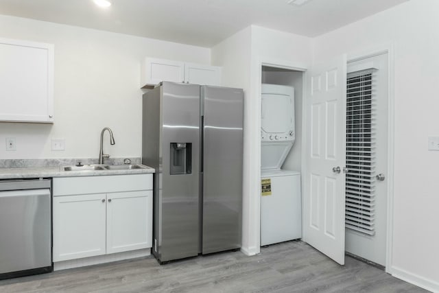 kitchen with white cabinets, sink, appliances with stainless steel finishes, and stacked washer and clothes dryer