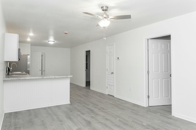 kitchen with kitchen peninsula, ceiling fan, sink, light hardwood / wood-style flooring, and white cabinets