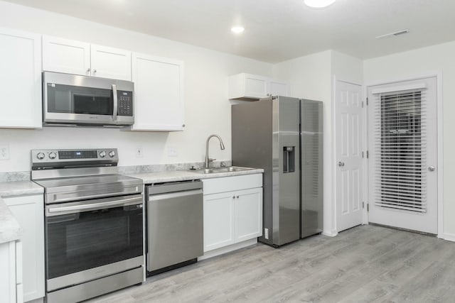 kitchen featuring white cabinetry, sink, light hardwood / wood-style floors, and appliances with stainless steel finishes