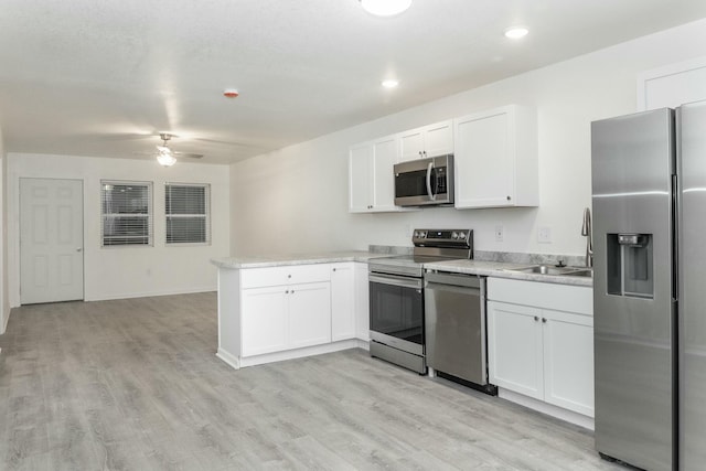 kitchen featuring ceiling fan, sink, kitchen peninsula, white cabinets, and appliances with stainless steel finishes