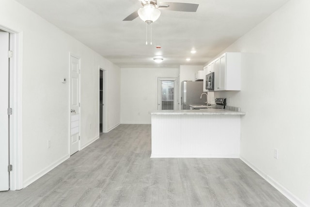 kitchen featuring white cabinetry, ceiling fan, kitchen peninsula, appliances with stainless steel finishes, and light wood-type flooring