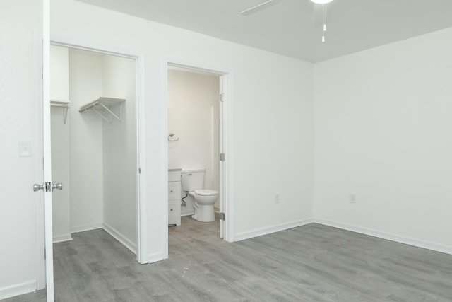 unfurnished bedroom featuring ensuite bath, a spacious closet, and light hardwood / wood-style floors