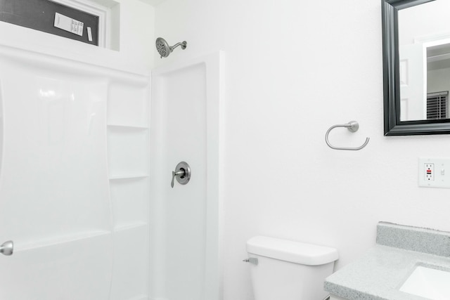 bathroom with walk in shower, vanity, and toilet