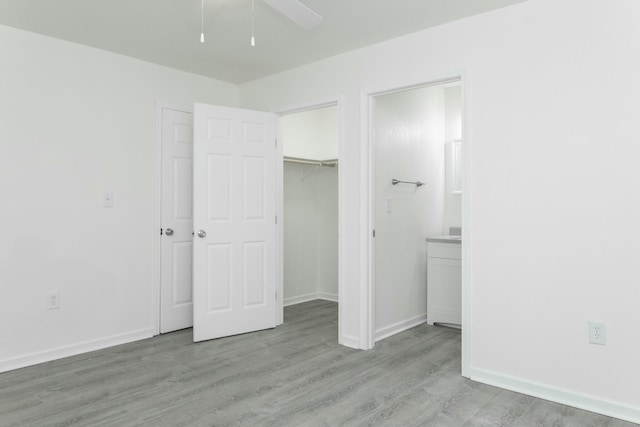 unfurnished bedroom featuring a closet, ceiling fan, light hardwood / wood-style flooring, and a spacious closet