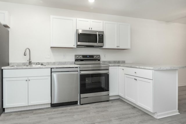 kitchen with light hardwood / wood-style floors, sink, white cabinetry, and stainless steel appliances