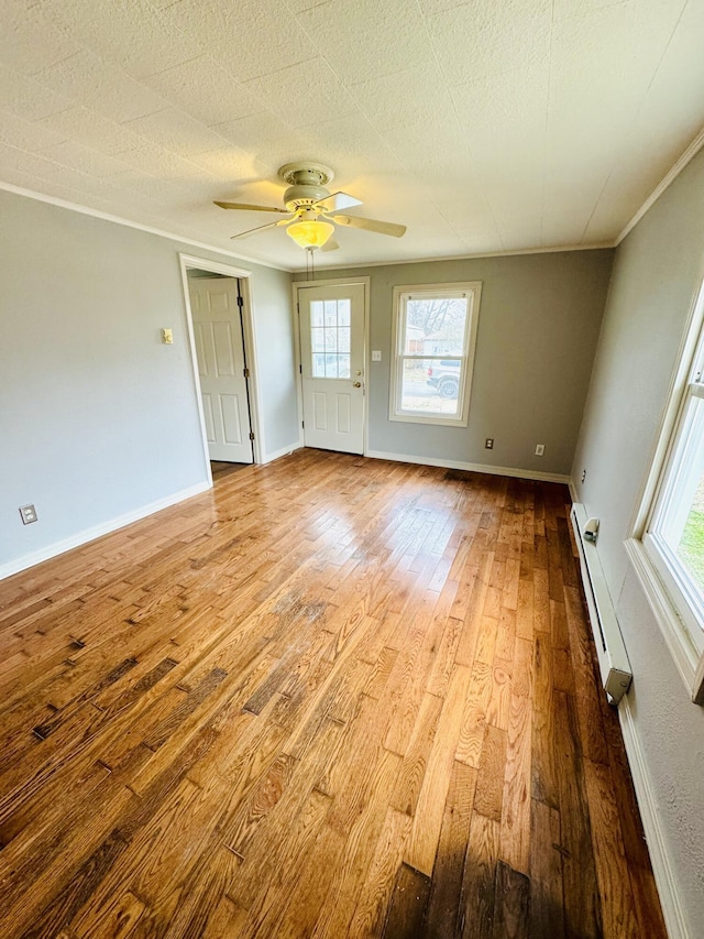 spare room featuring ornamental molding, a baseboard radiator, plenty of natural light, and light hardwood / wood-style floors