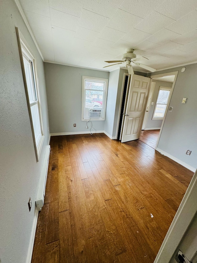 spare room with hardwood / wood-style floors, a baseboard radiator, ceiling fan, and crown molding