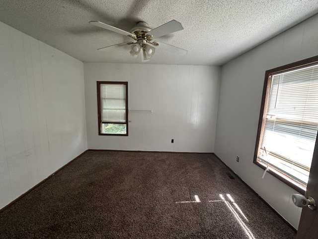 carpeted empty room featuring plenty of natural light, ceiling fan, and a textured ceiling