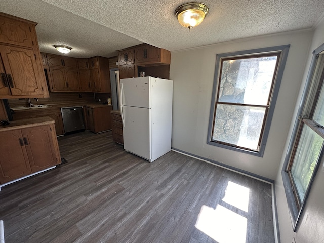 kitchen featuring dark hardwood / wood-style floors, stainless steel dishwasher, a textured ceiling, and white refrigerator