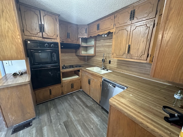 kitchen with a textured ceiling, oven, stainless steel dishwasher, and sink