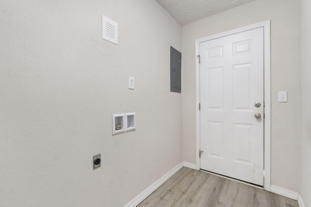 laundry area with hookup for an electric dryer, hookup for a washing machine, a textured ceiling, light hardwood / wood-style flooring, and electric panel