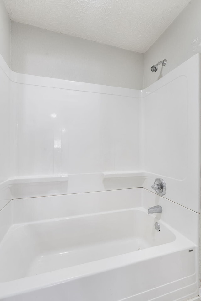 bathroom with a textured ceiling and tub / shower combination