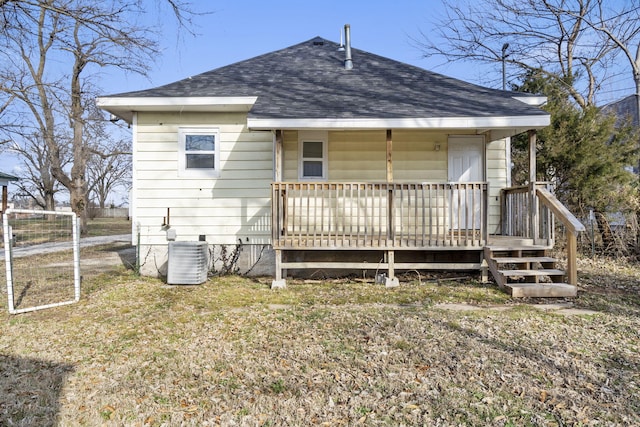 rear view of house with central AC and a lawn