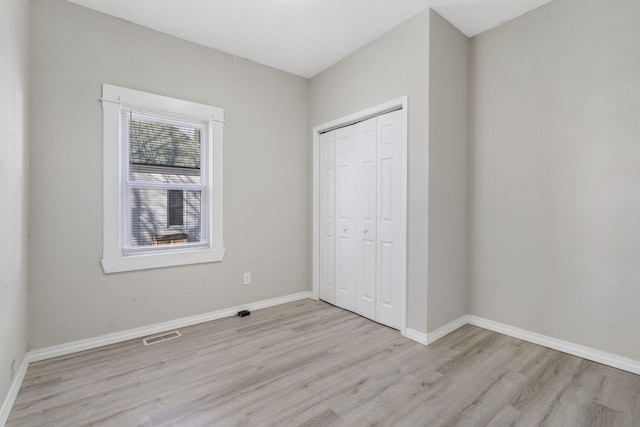 unfurnished bedroom featuring light hardwood / wood-style flooring and a closet