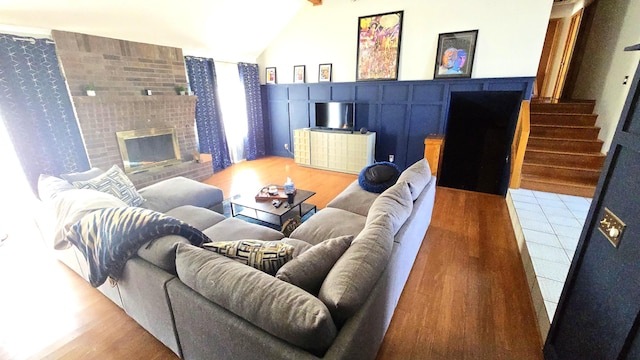 living room with a tile fireplace, wood-type flooring, and lofted ceiling with beams