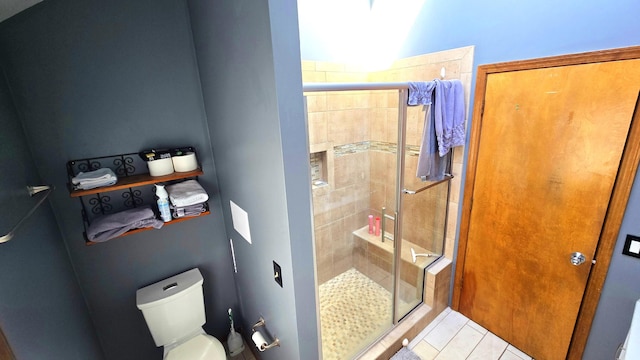 bathroom featuring tile patterned flooring, toilet, and a shower with shower door