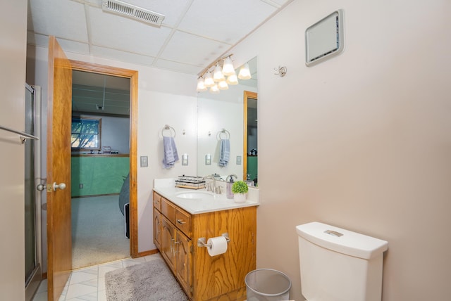 bathroom featuring a paneled ceiling, tile patterned flooring, vanity, and toilet