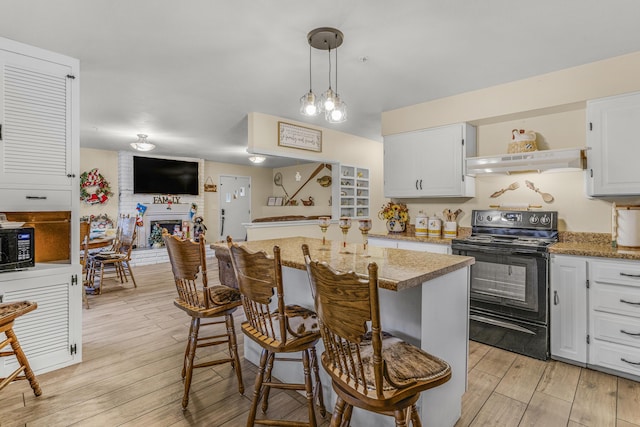 kitchen with white cabinetry, ventilation hood, pendant lighting, a fireplace, and black appliances