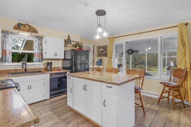 kitchen featuring pendant lighting, a center island, black appliances, white cabinets, and a kitchen bar