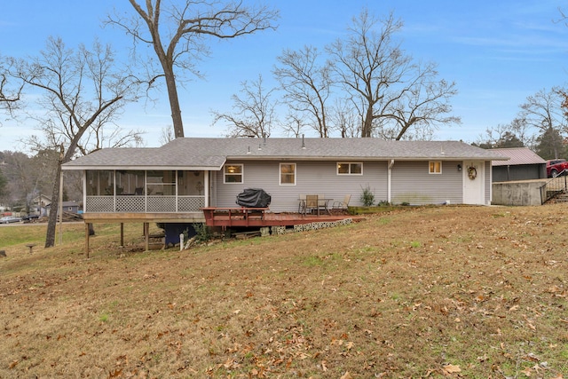 rear view of house featuring a lawn, a wooden deck, and a sunroom