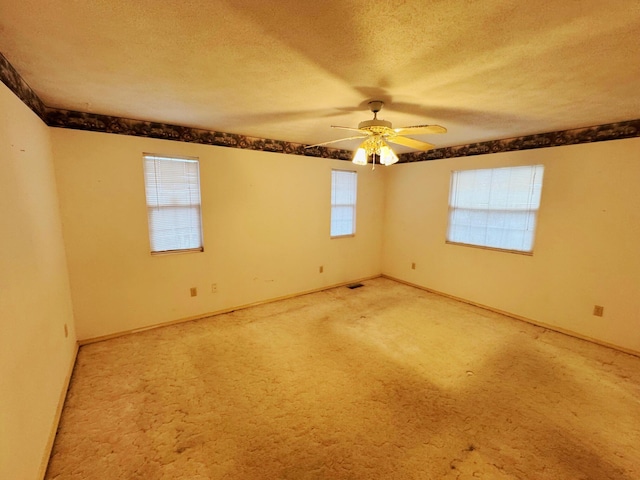 carpeted empty room featuring ceiling fan and a textured ceiling