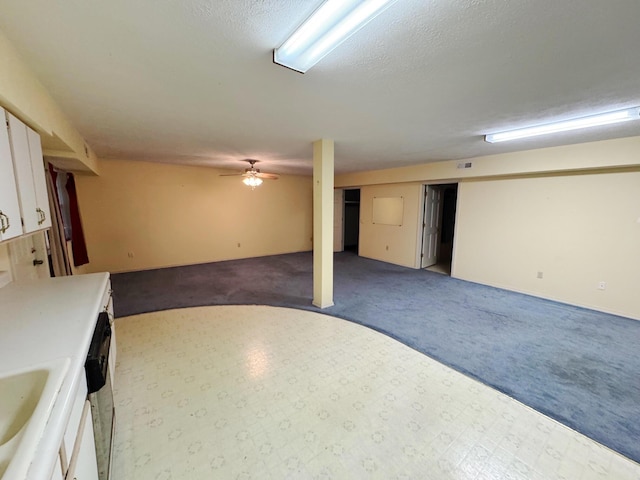 basement with a textured ceiling, carpet floors, and sink