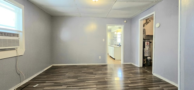 spare room featuring water heater, sink, a drop ceiling, and dark hardwood / wood-style floors