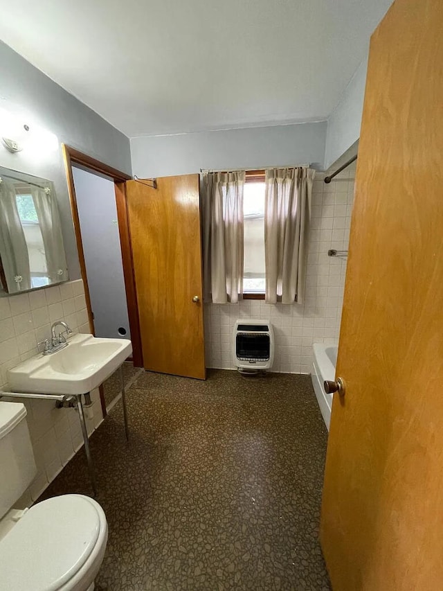 bathroom with sink, heating unit, tile walls, and toilet