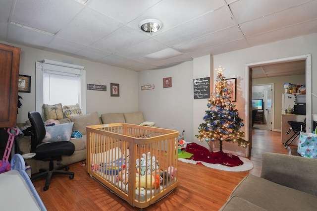 bedroom featuring a paneled ceiling, wood-type flooring, and a crib