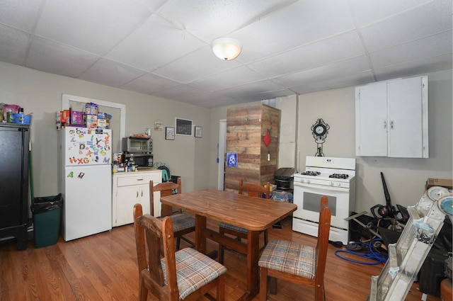 kitchen featuring white cabinets, a drop ceiling, light hardwood / wood-style floors, and white appliances