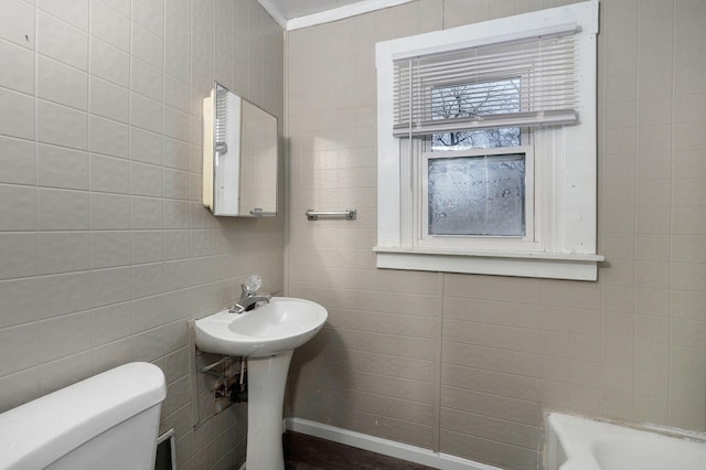 bathroom with a bathing tub, toilet, and ornamental molding