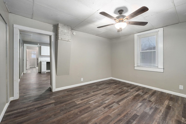 unfurnished room featuring a paneled ceiling, ceiling fan, and dark hardwood / wood-style flooring