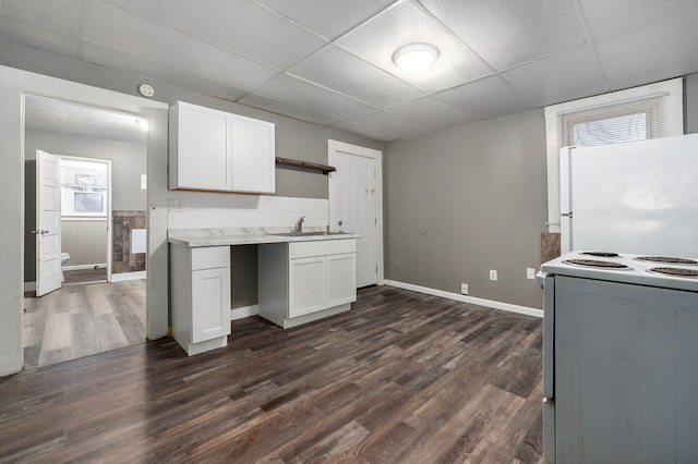 kitchen with a paneled ceiling, white fridge, range, and white cabinetry