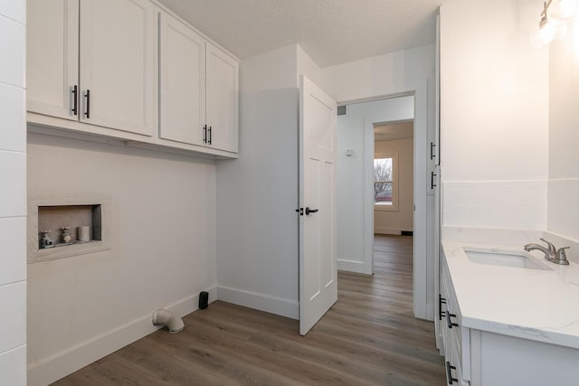 washroom with cabinets, hookup for a washing machine, dark hardwood / wood-style flooring, a textured ceiling, and sink