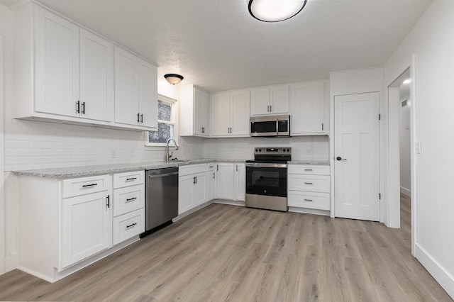 kitchen featuring white cabinetry, sink, decorative backsplash, appliances with stainless steel finishes, and light wood-type flooring