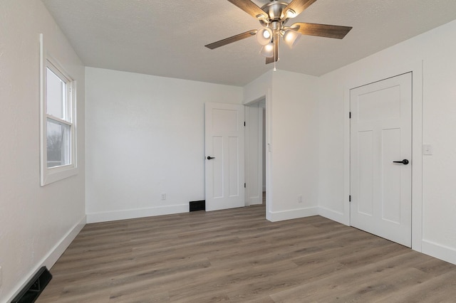 interior space featuring ceiling fan, dark wood-type flooring, and a textured ceiling