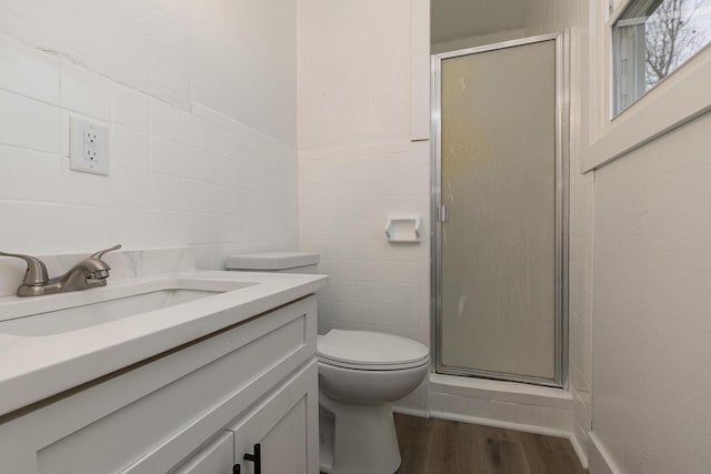 bathroom featuring hardwood / wood-style floors, an enclosed shower, toilet, vanity, and tile walls