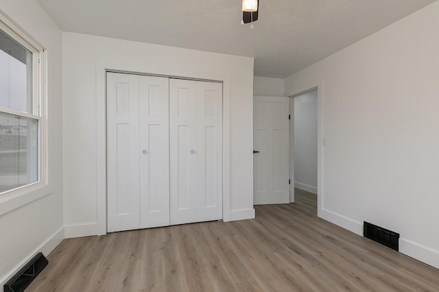 unfurnished bedroom with a closet, light hardwood / wood-style floors, and ceiling fan