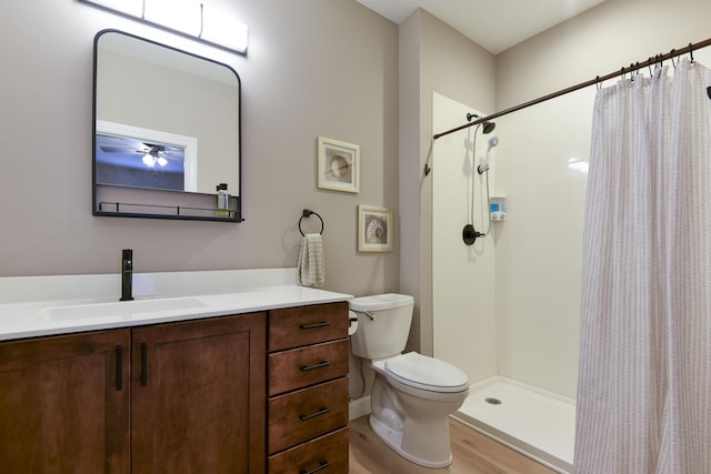 bathroom with hardwood / wood-style floors, vanity, toilet, and walk in shower