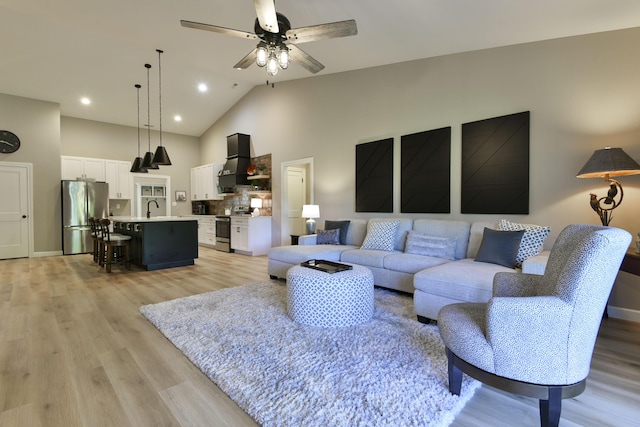 living room featuring ceiling fan, light wood-type flooring, sink, and high vaulted ceiling