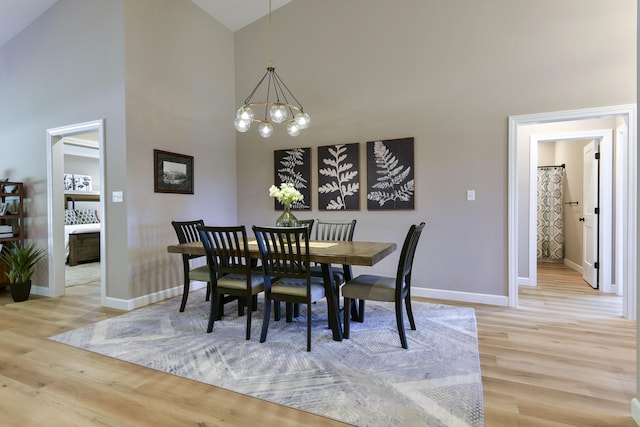 dining area featuring an inviting chandelier, hardwood / wood-style flooring, and high vaulted ceiling