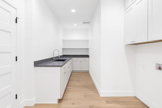 kitchen with white cabinetry, sink, and light hardwood / wood-style flooring