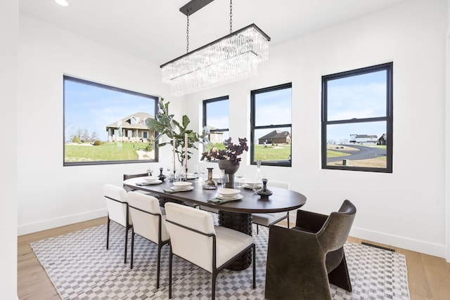 dining space with plenty of natural light, an inviting chandelier, and light wood-type flooring