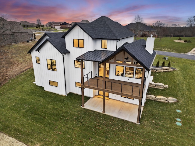 back house at dusk featuring a patio area and a yard