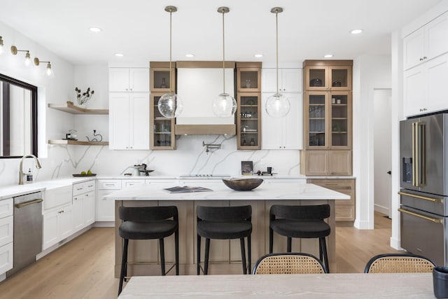 kitchen featuring appliances with stainless steel finishes, light hardwood / wood-style flooring, a kitchen island, and hanging light fixtures