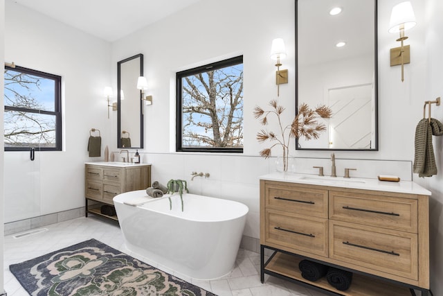 bathroom featuring vanity, a tub to relax in, and tile walls