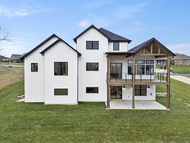 rear view of house featuring a balcony, a patio area, and a lawn